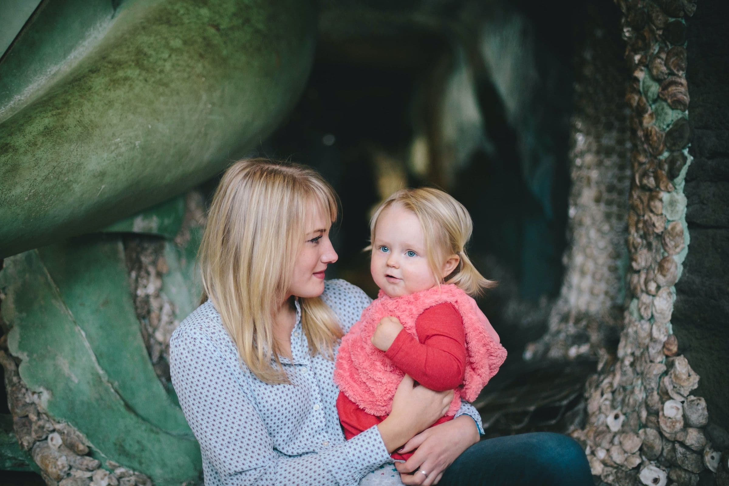 Woman holding a young child with tropical looking plants in the background